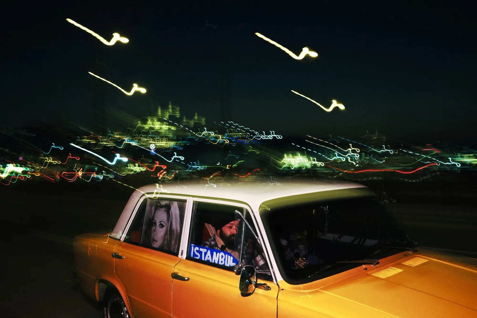 Orangefarbenes Auto bei Nacht mit Lichtspuren