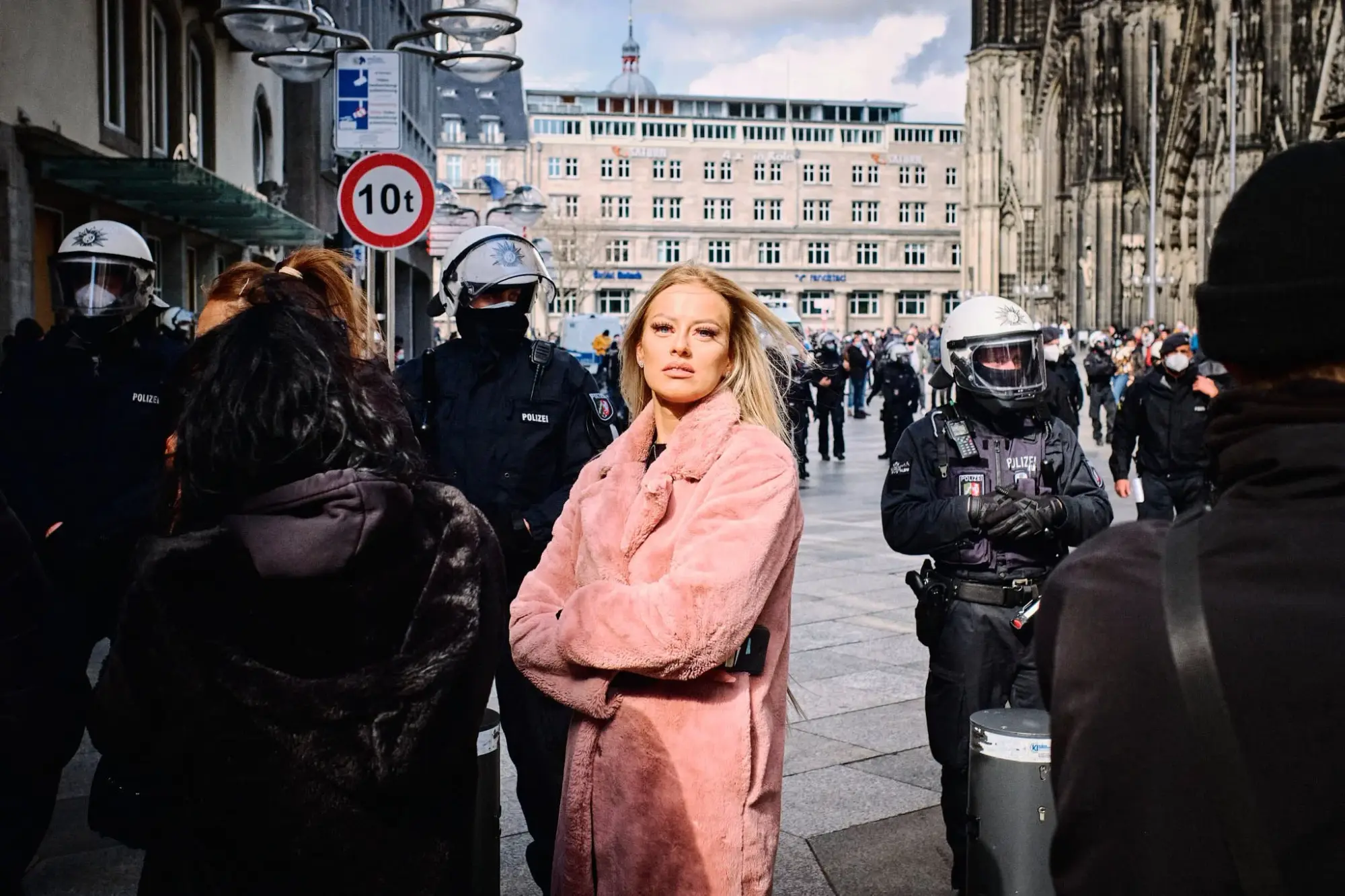 Frau in pinkem Mantel vor der Polizei