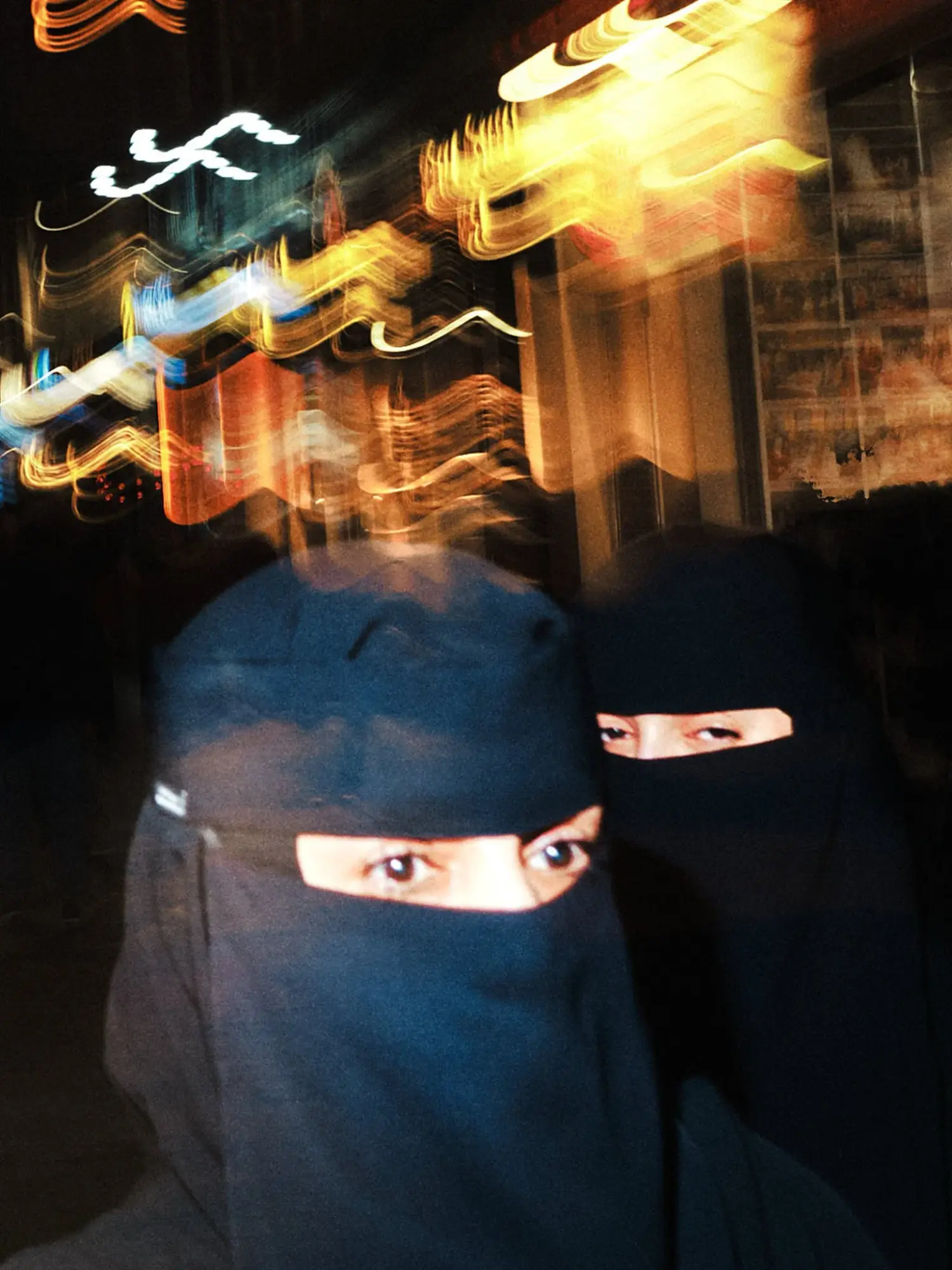 Zwei Personen in schwarzen Burkas bei Nacht